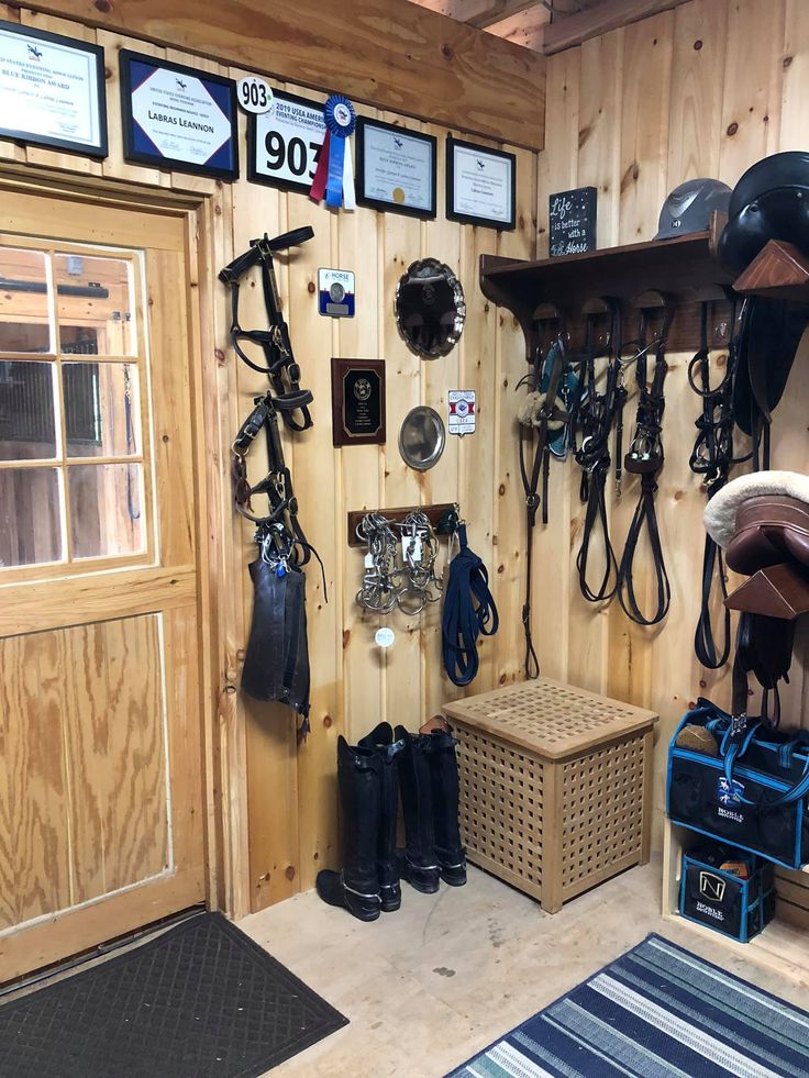 the inside of a horse stable with lots of tacks and hats hanging on the wall