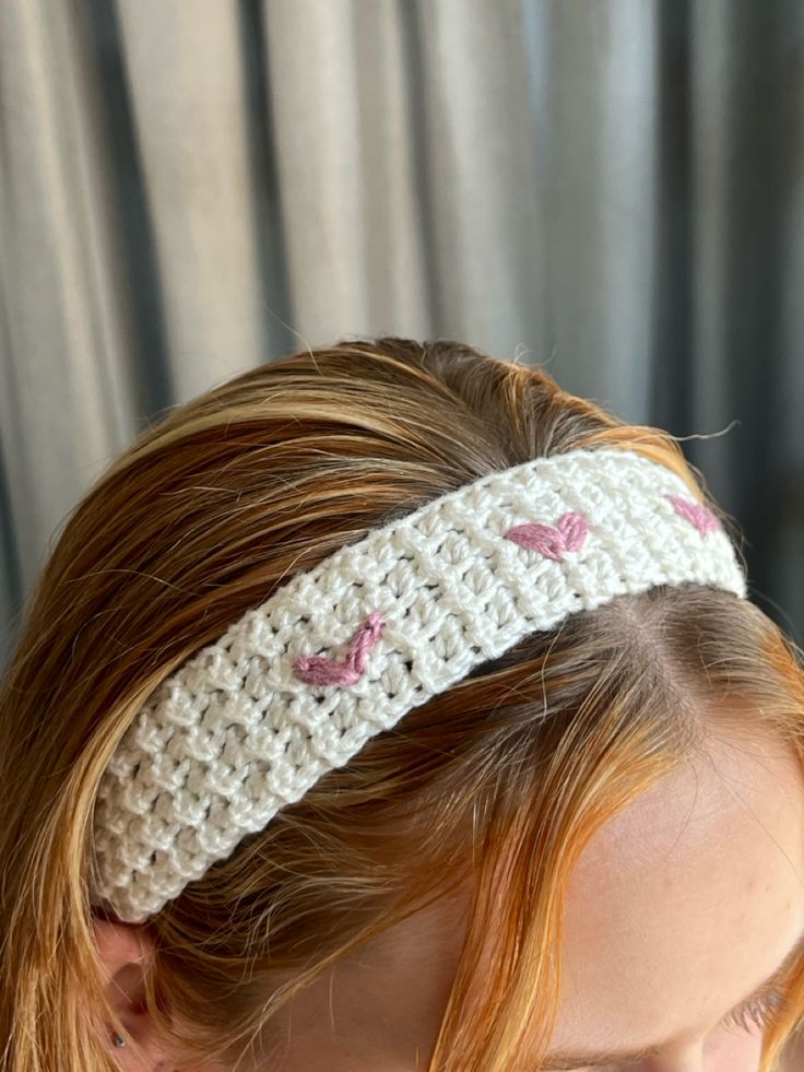 a woman wearing a white headband with pink hearts on it