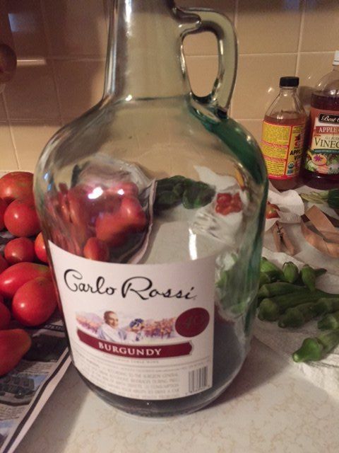 a glass bottle filled with fruit sitting on top of a counter next to other fruits