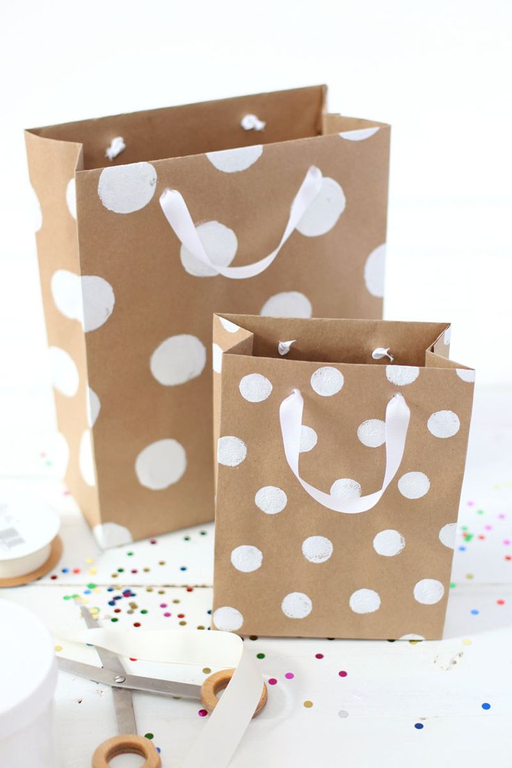 three brown paper bags with white polka dots on them and scissors next to the bag