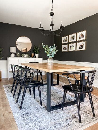 a dining room table with four chairs and a rug on the floor in front of it