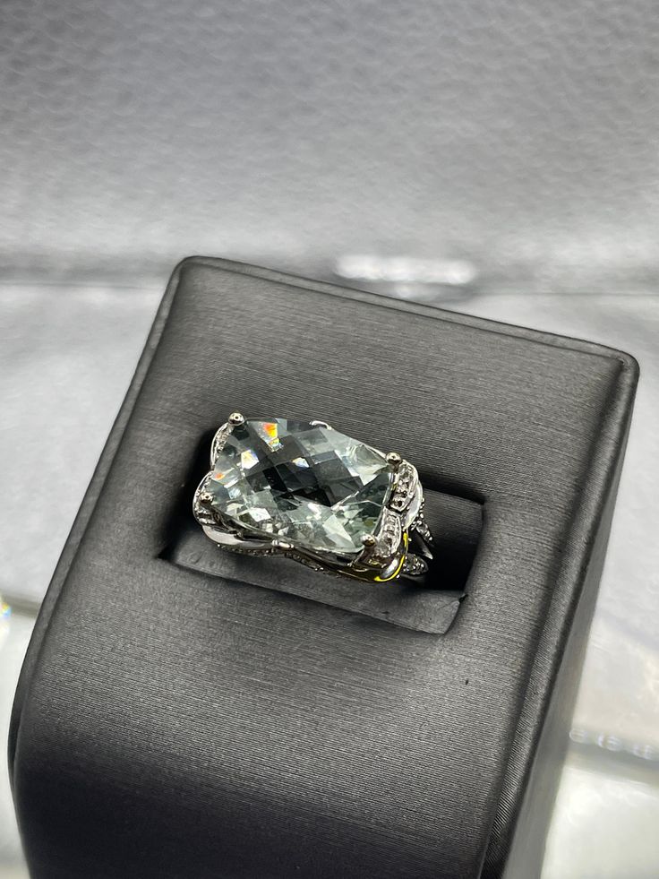 A dazzling 8 carat Blue Obsidian stone cut in a checkerboard pattern set with 75 pts of diamonds.  The ring is beautifully designed in 14 karat solid white gold with an ornate diamond setting throughout the outside of the ring. TDW:  0.75 cts Weight:  5.3 grams Size:  5 ½  Our Price $1500.00 Regularly Priced At $1900.00 Please See Our Video Remember - If you're purchasing for yourself or a gift for a loved one, buy with confidence.  We Guarantee Everything We Sell!  SKU # R948 Luxury Topaz Ring With Diamond Accents, Luxury Gemstones With Diamond Accents, Luxury Platinum Gemstones With Accent Stones, Luxury Diamond Gemstones For Formal Occasions, Luxury Diamond White Topaz Ring, Fine Jewelry Diamond Gemstones With Diamond Cut, Luxury Platinum Topaz Gemstone Ring, Luxury Diamond Topaz Ring With Cushion Cut, Luxury Platinum Topaz Ring With Accent Stones