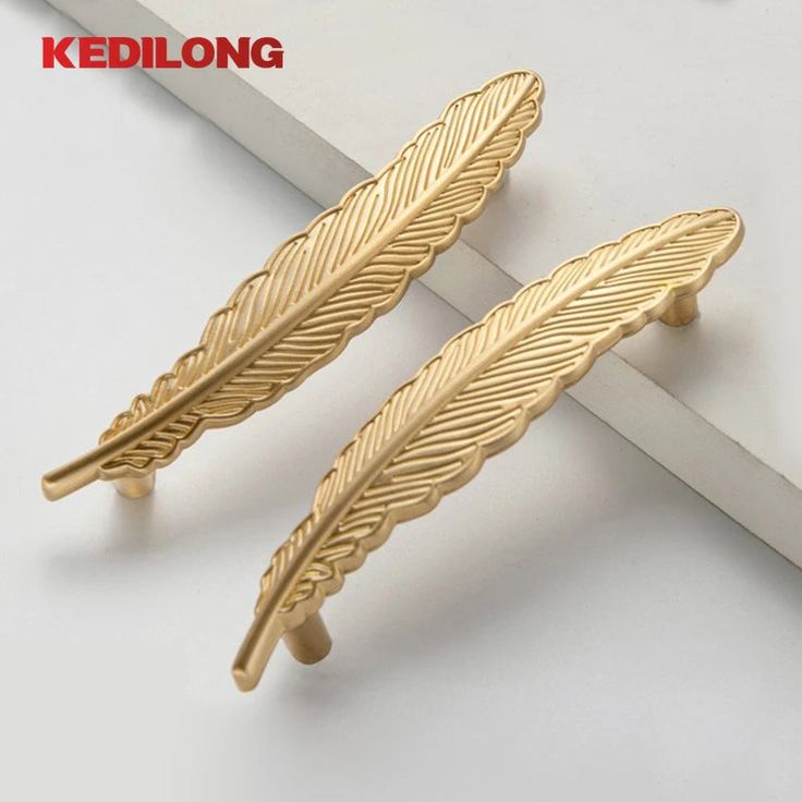 two pairs of gold tone feather shaped cabinet knobs on a white surface with the words kedlong