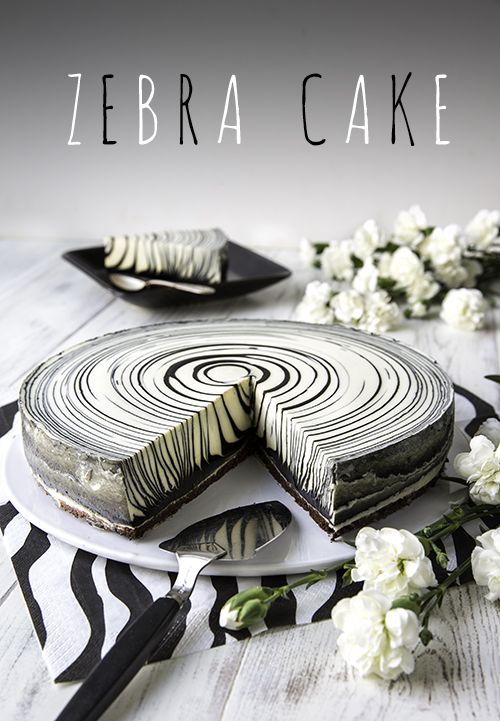 a zebra print cake with white flowers on the side and one slice missing from it