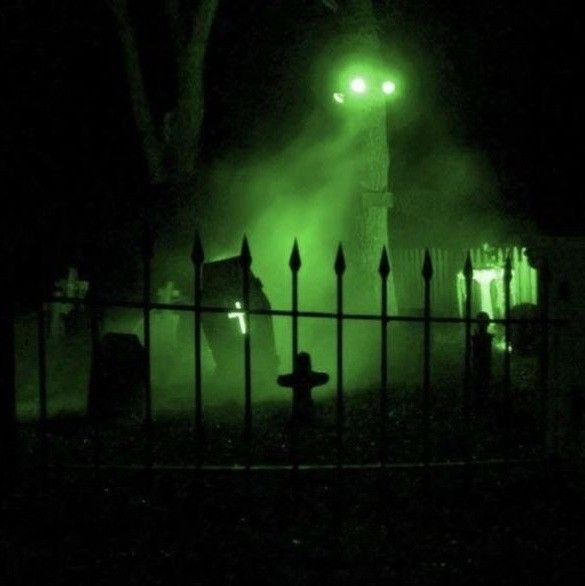 a green light shines in the dark over a cemetery