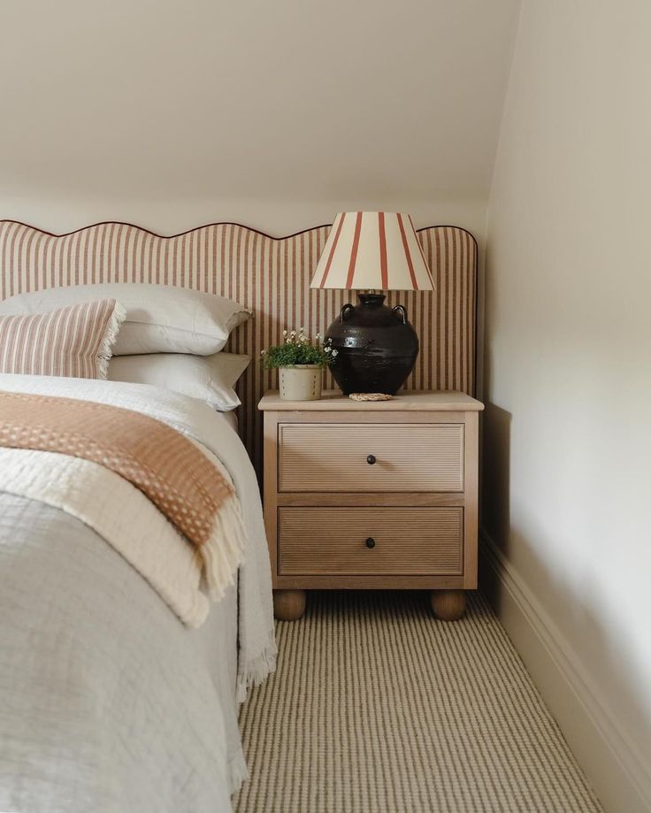 a bed room with a neatly made bed and a night stand next to the bed