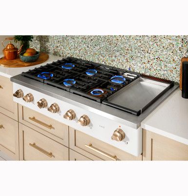 a stove top oven sitting inside of a kitchen next to wooden cabinets and counter tops