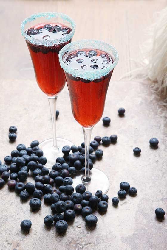 two glasses filled with blueberries on top of a table