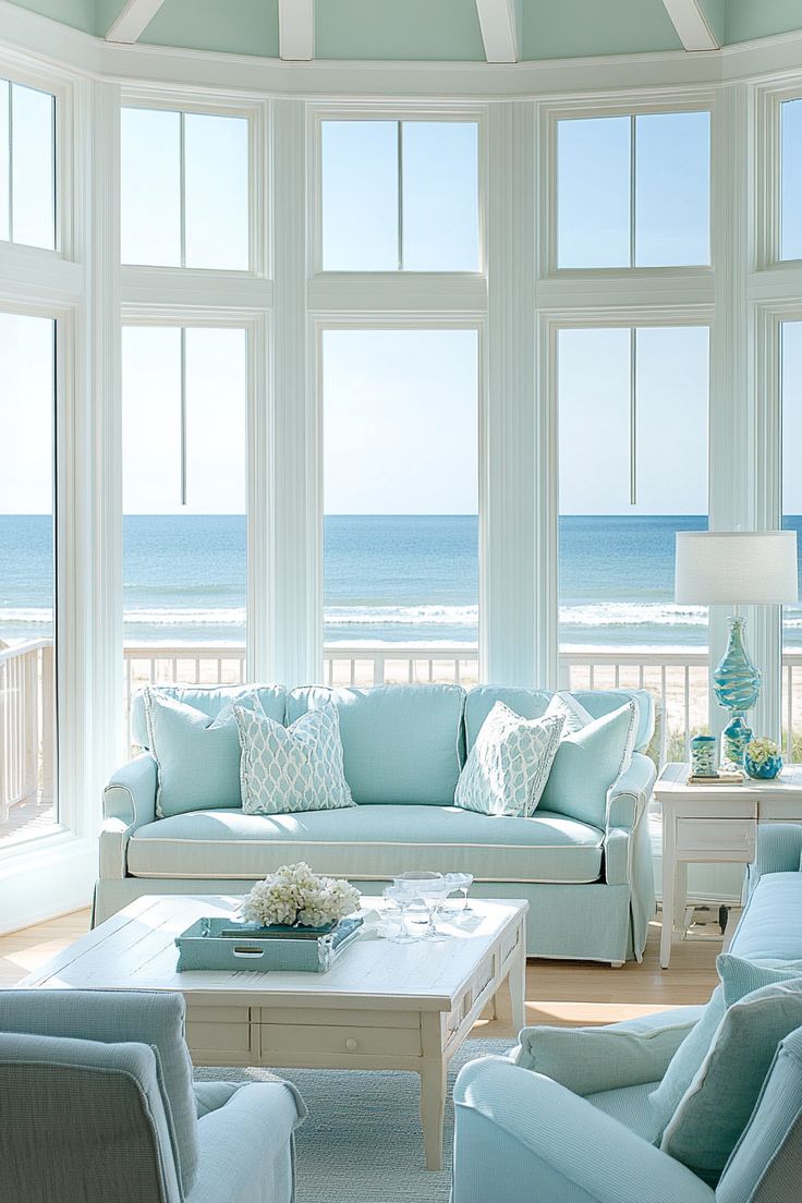 a living room filled with lots of furniture and large windows overlooking the beach in front of it