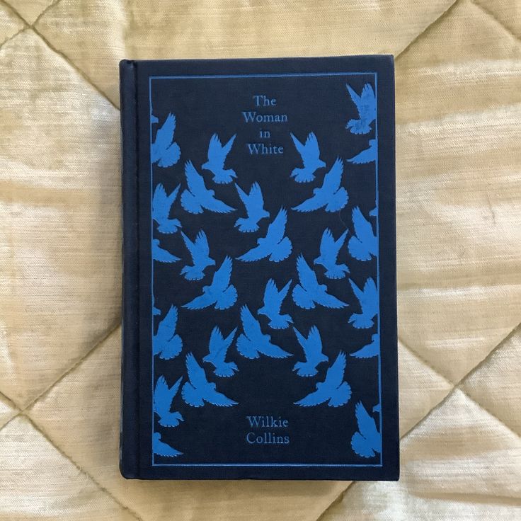 a book with blue birds on it sitting on top of a bed covered in sheets