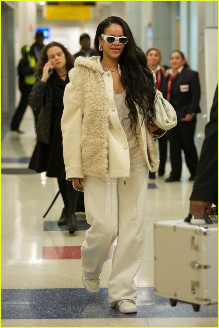 a woman in white is walking through an airport with her luggage and she's wearing sunglasses