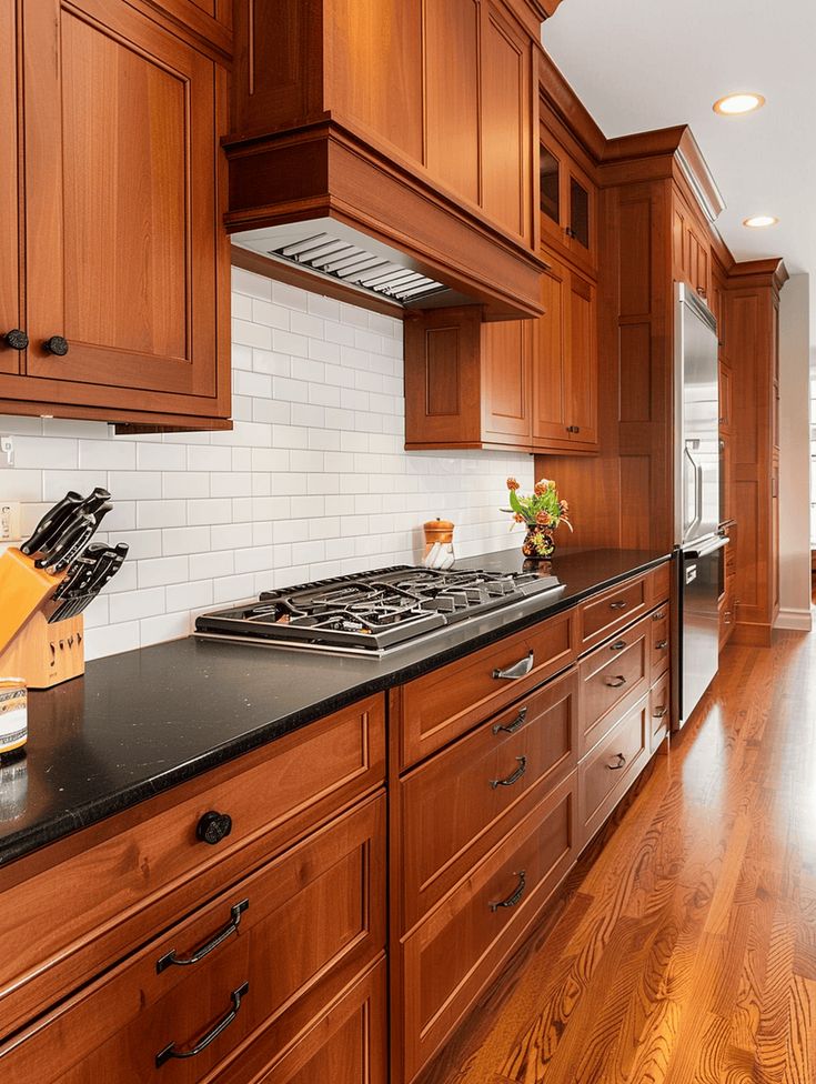 a kitchen with wooden cabinets and black counter tops, along with hardwood flooring that matches the walls