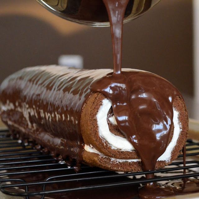 there is a chocolate roll being drizzled with icing