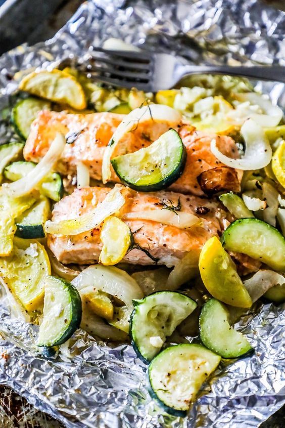 grilled salmon and zucchini on foil with a fork next to it, ready to be eaten