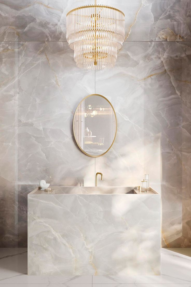 an elegant bathroom with marble walls and flooring, gold chandelier above the sink