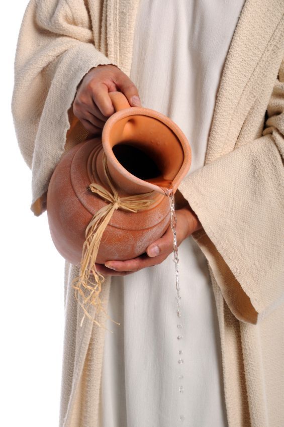 a man holding a clay pot in his hands and wearing a white robe on top of it