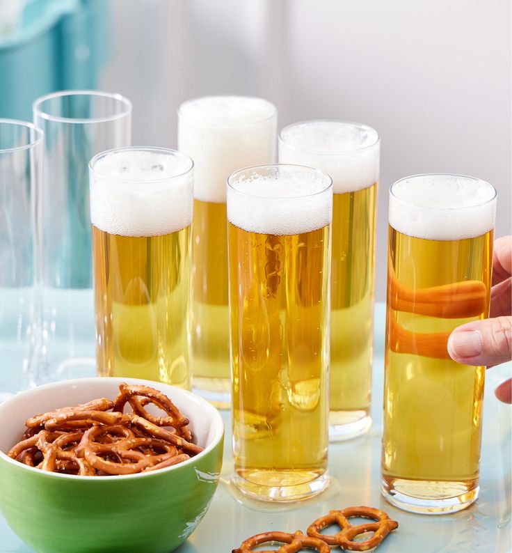 beer and pretzels are being served in glasses on a table with other drinks