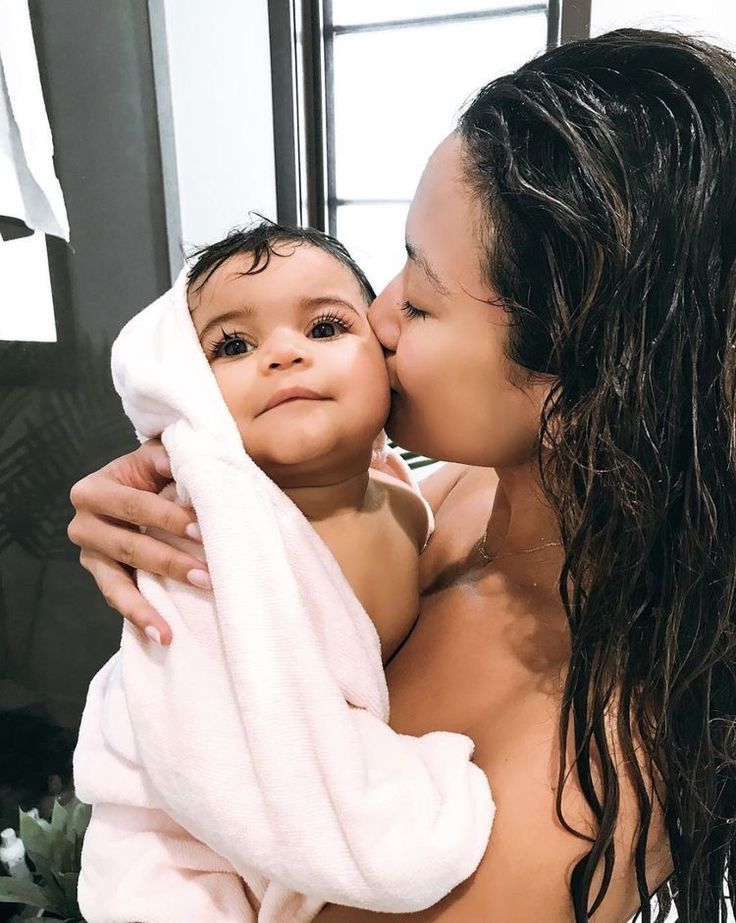 a woman is holding a baby wrapped in a towel and kissing her face with both hands