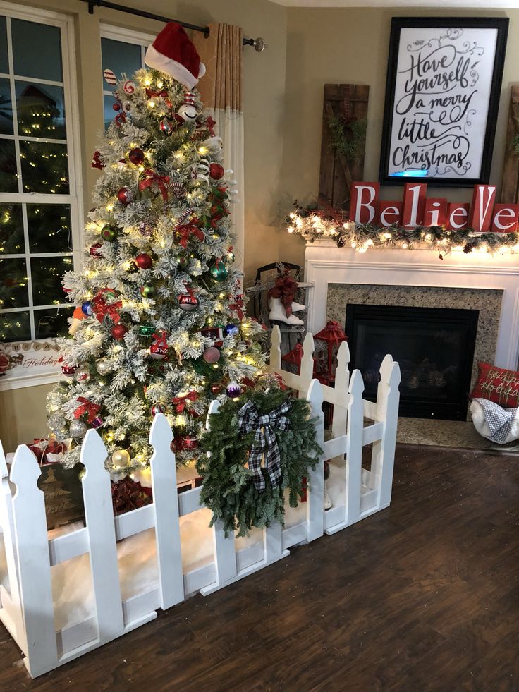 a decorated christmas tree in the corner of a living room next to a white picket fence