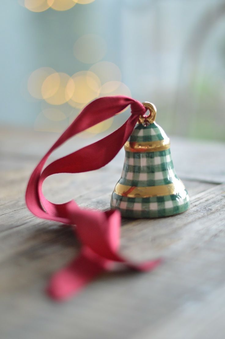 a small christmas tree ornament with a red ribbon tied around it on a wooden table