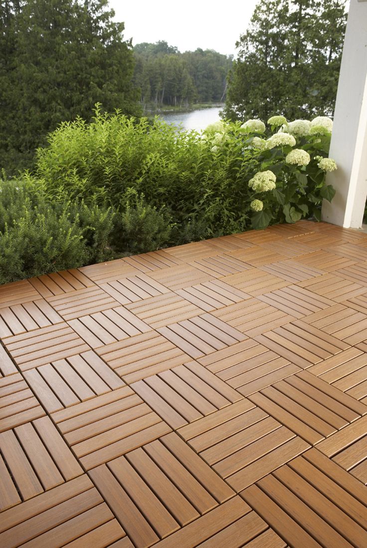 a wooden deck with white flowers and bushes in the background