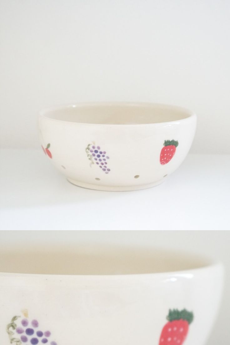 two bowls with fruit designs on them sitting side by side in front of each other