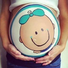 a pregnant woman's belly with a smiling face painted on it