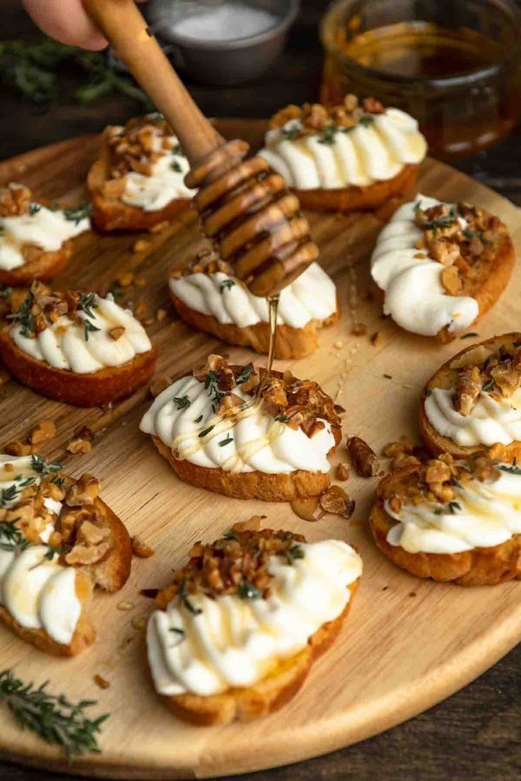 a wooden plate topped with mini cakes covered in whipped cream