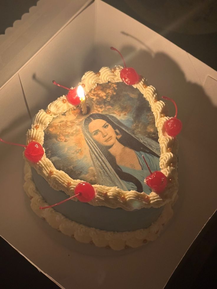 a cake in a box with an image of the virgin mary on it and candles