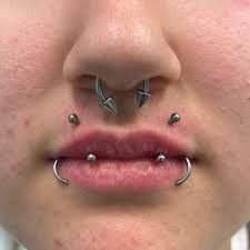 a woman's nose with two piercings on the middle of her nose and one behind her head