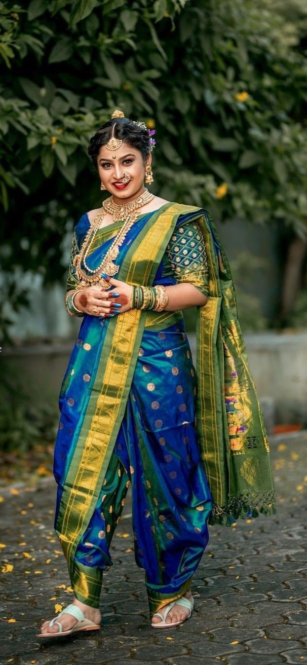 a woman in a blue and yellow sari is standing on the street with her arms crossed