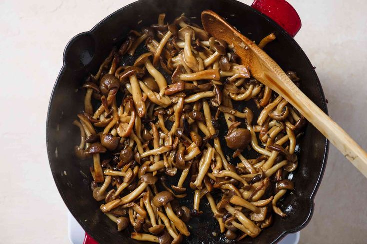 mushrooms are being cooked in a skillet with wooden spoon