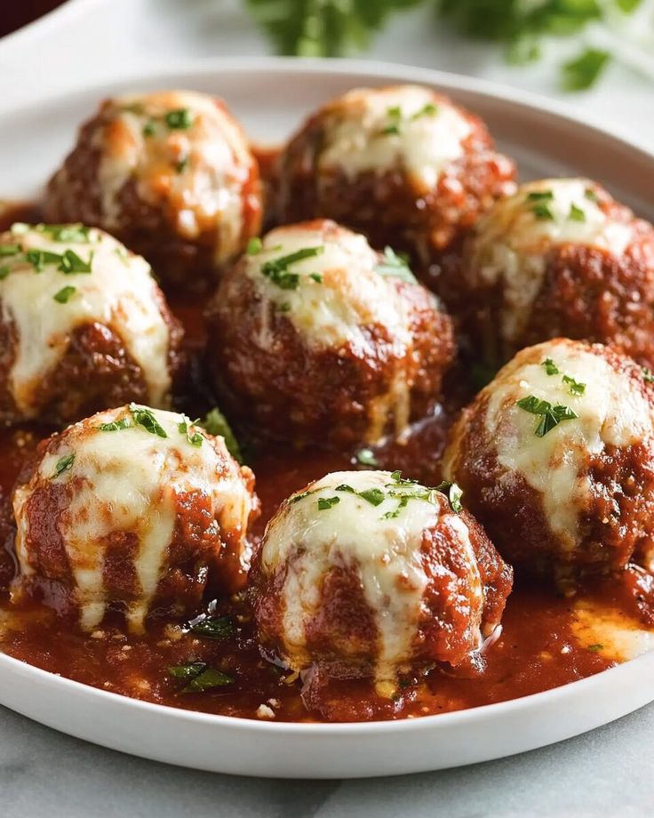 meatballs covered in marinara sauce and parsley on top of a white plate