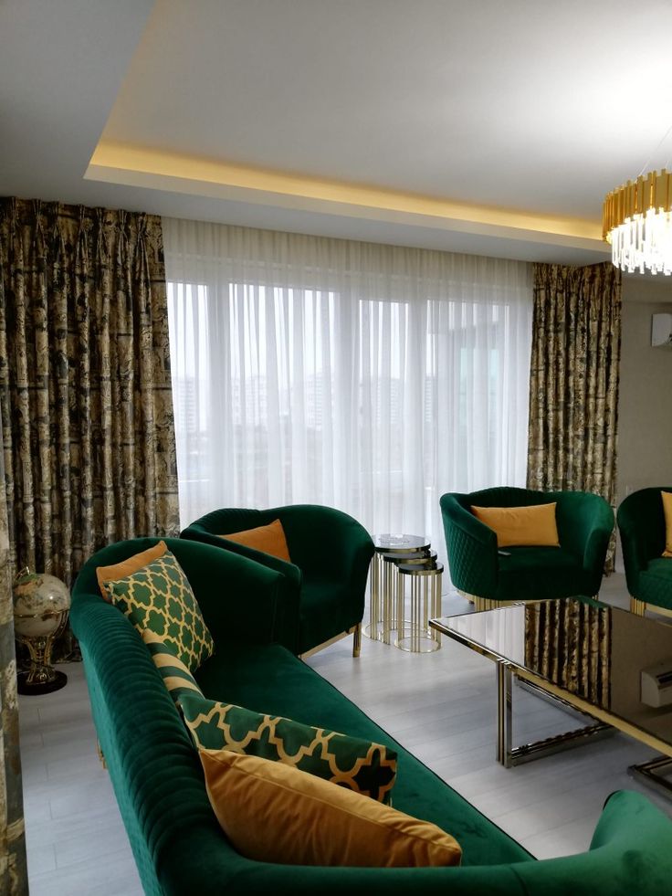 a living room filled with green couches next to a tall window covered in curtains