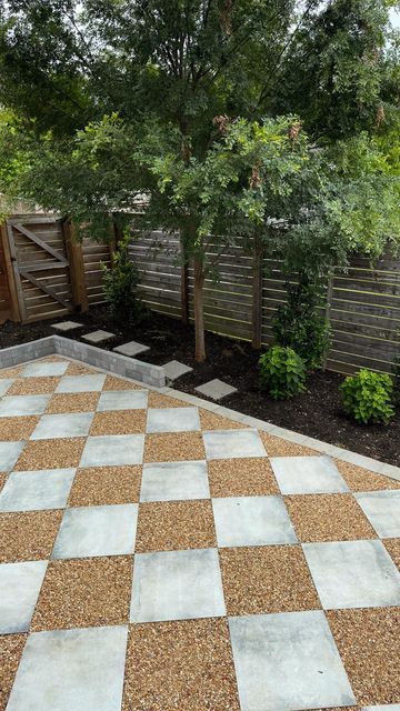 a large checkerboard pattern is in the middle of a garden area with trees and shrubbery