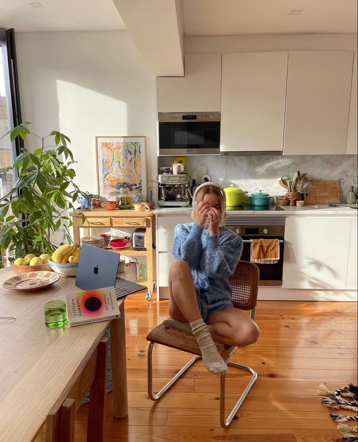 a woman is sitting on a chair in the kitchen