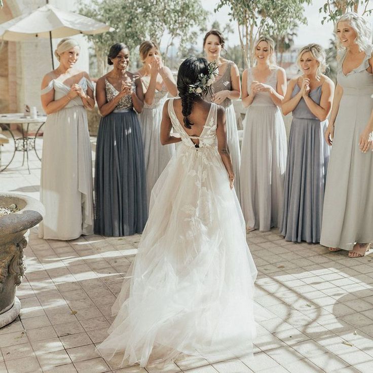 a group of women standing around each other in long dresses and one woman wearing a dress