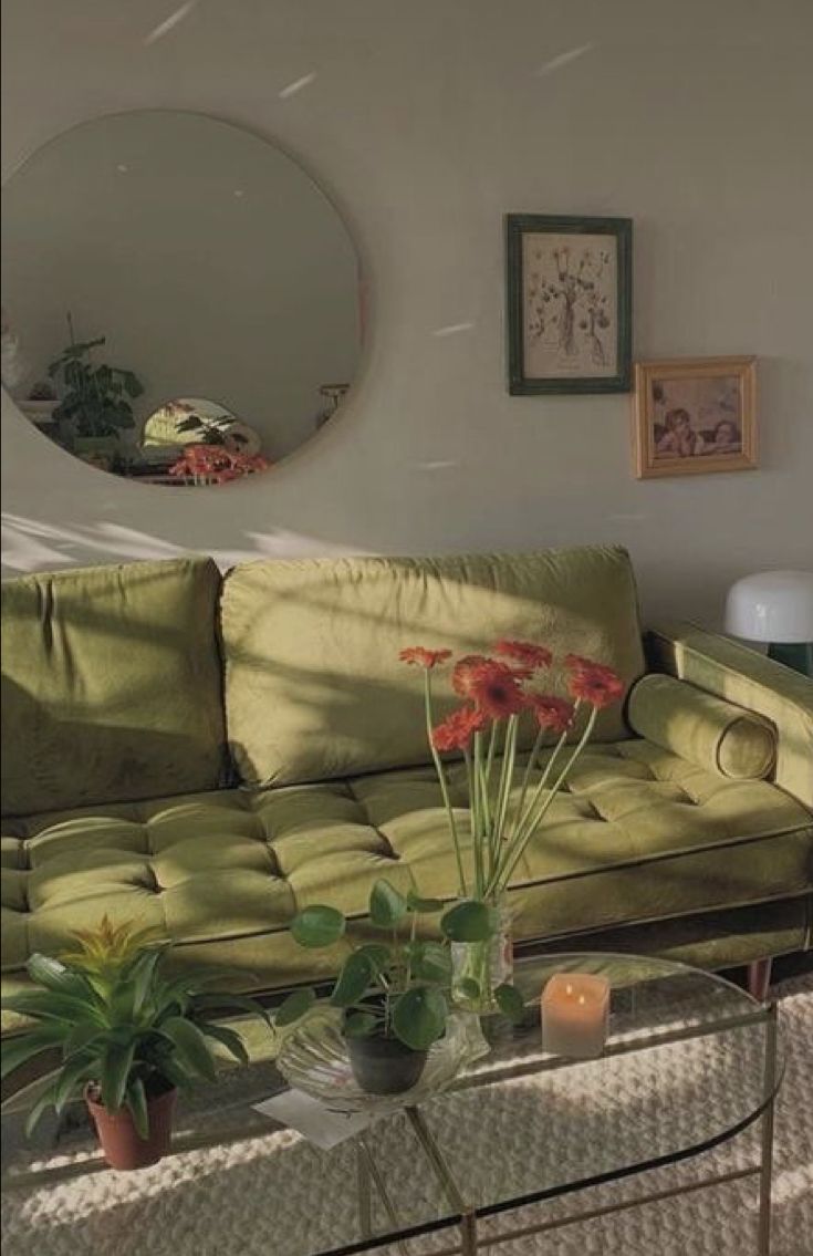 a living room with green couches and potted plants on the coffee table in front of it