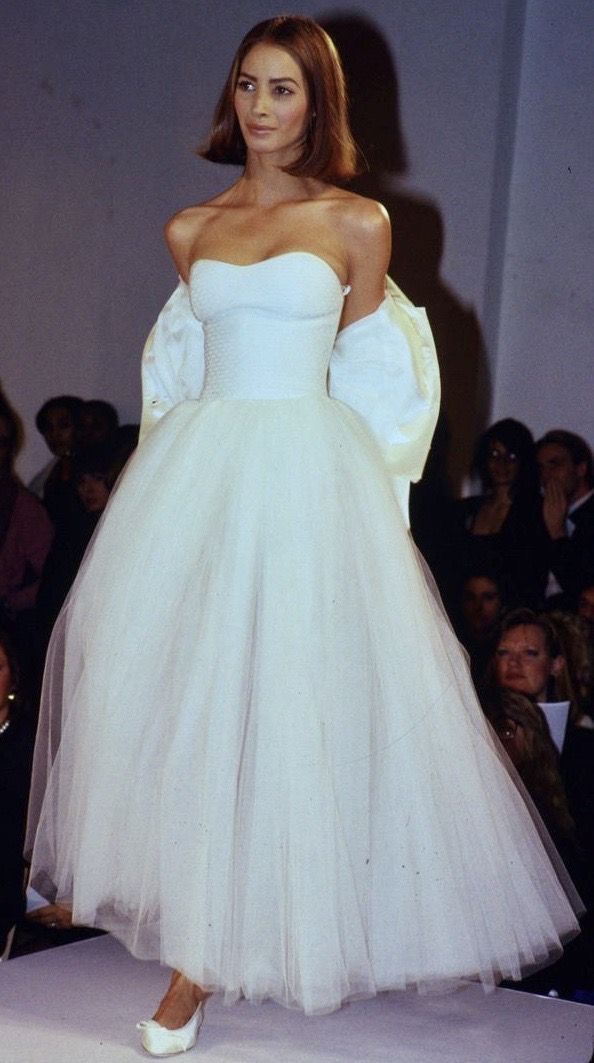 a woman in a white dress standing on a runway