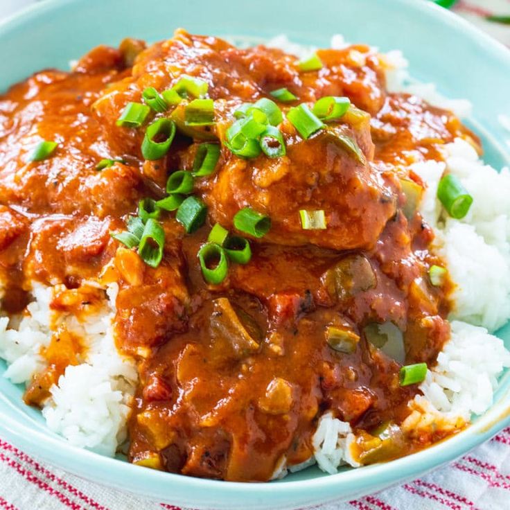 a blue bowl filled with rice and meat covered in gravy