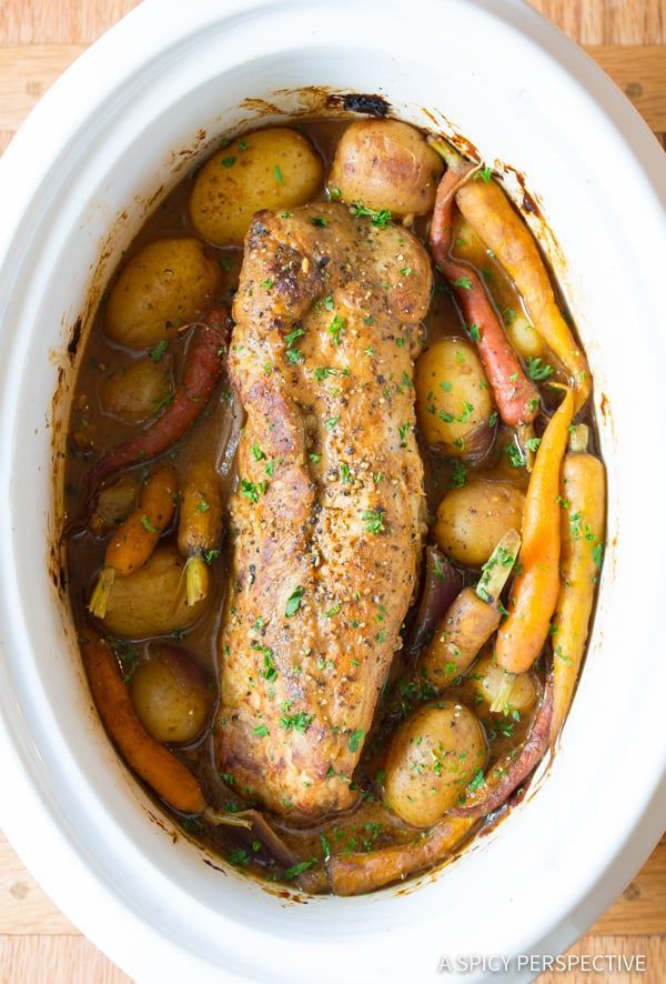 a white bowl filled with meat, potatoes and carrots on top of a wooden table