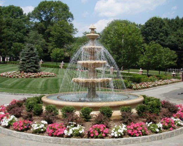 a large fountain surrounded by flowers and trees