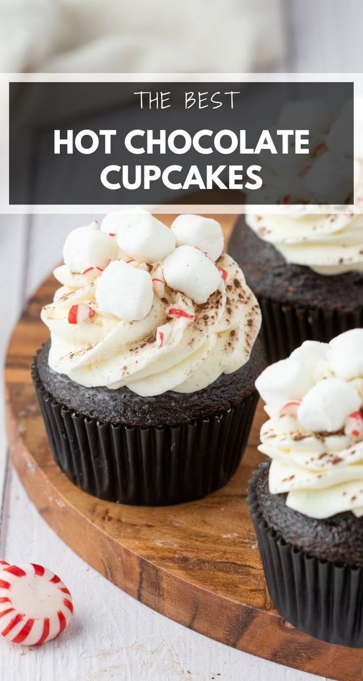 chocolate cupcakes with white frosting and peppermint on top are sitting on a wooden board