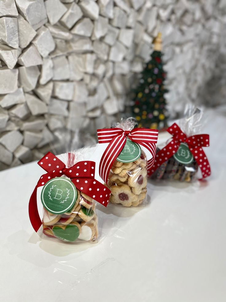 three bags of cookies sitting on top of a table next to a small christmas tree