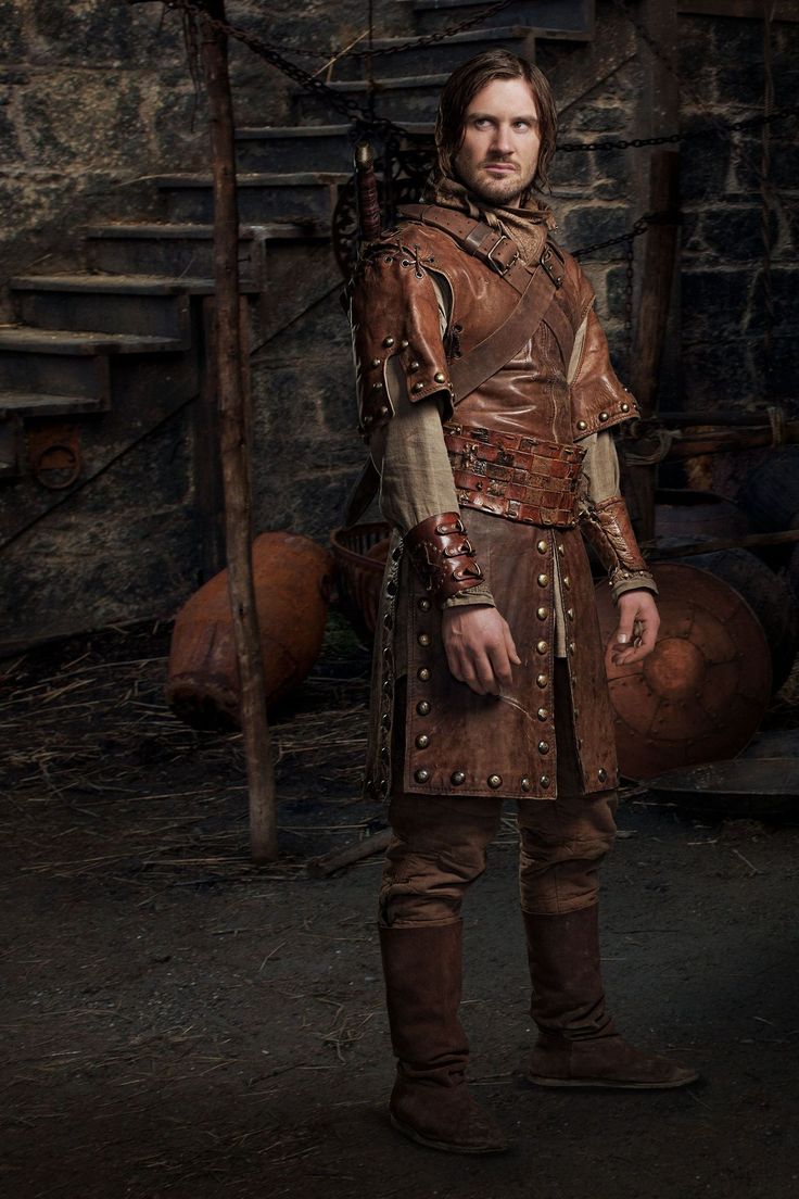 a man dressed in armor standing next to barrels