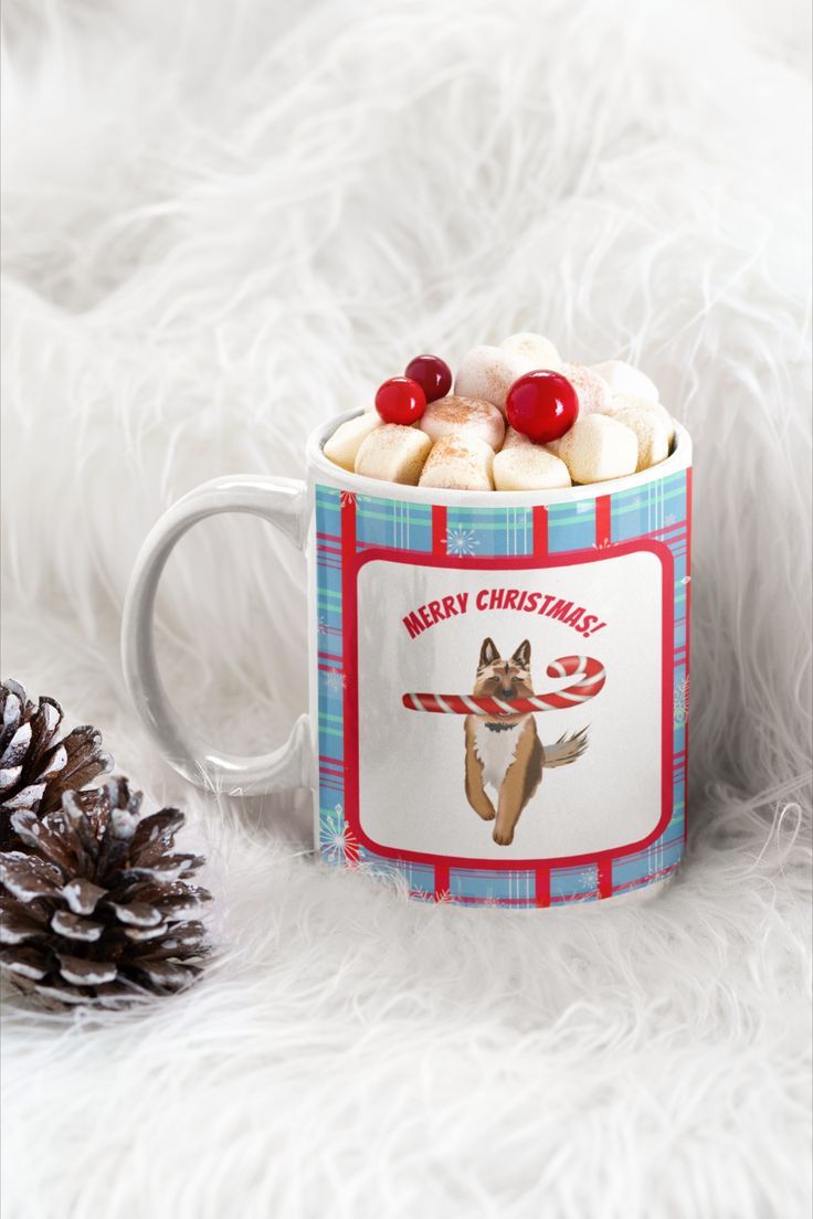 a christmas mug with marshmallows in it and a pine cone