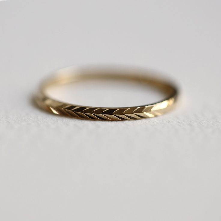 a gold wedding band on a white surface with the word love written in it and an arrow