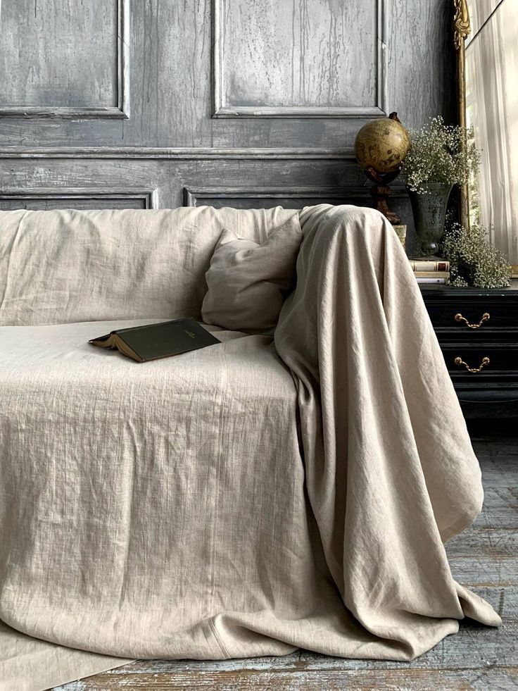 a couch covered with a blanket in front of a wooden wall and mirror behind it