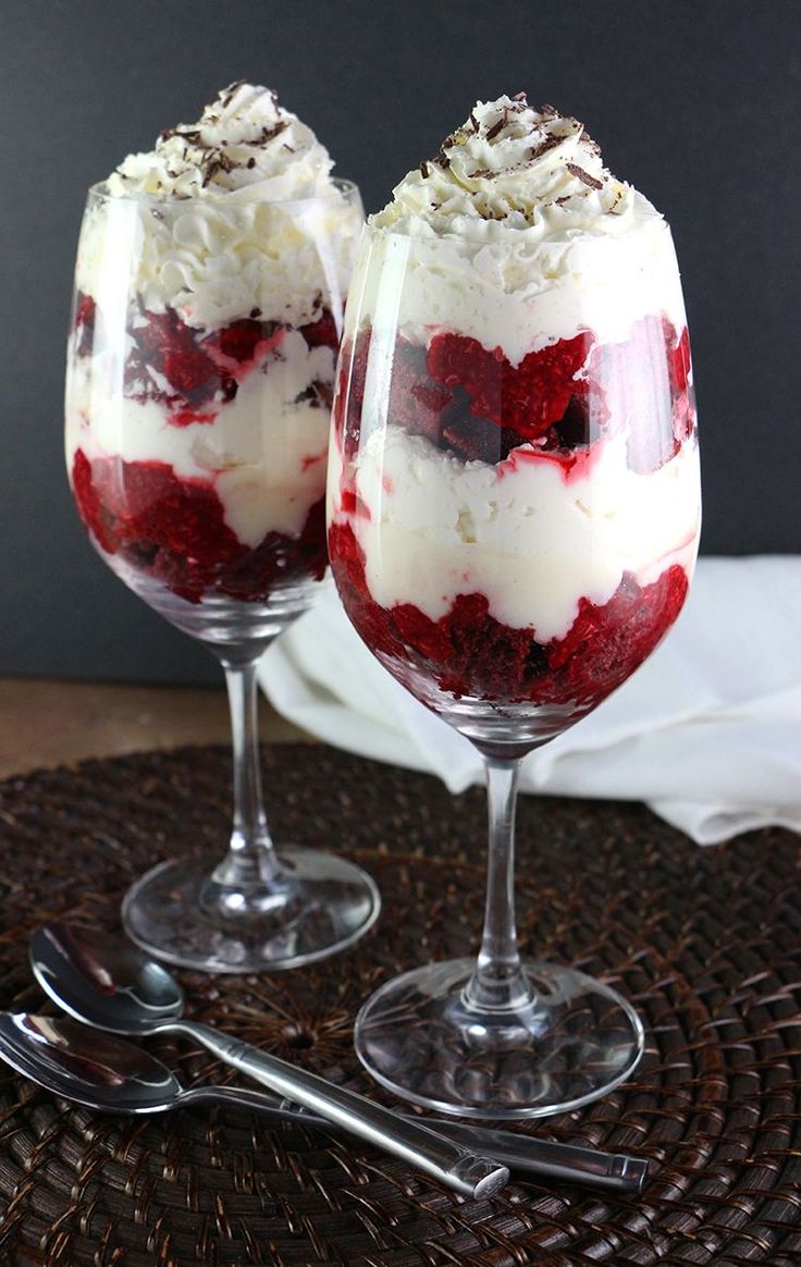 two glasses filled with dessert sitting on top of a table