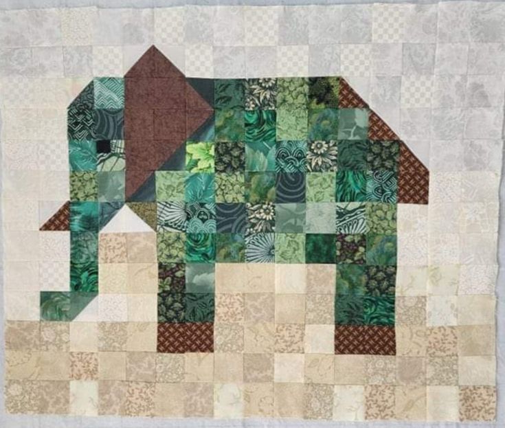 an elephant is made out of patchwork and has green leaves on the top of it